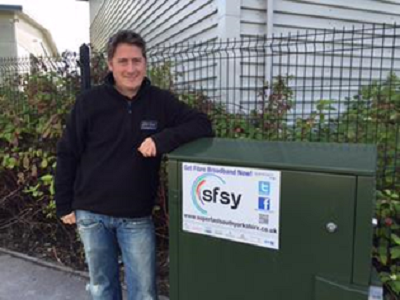 Photo of a man leaning on a superfast broadband street cabinet